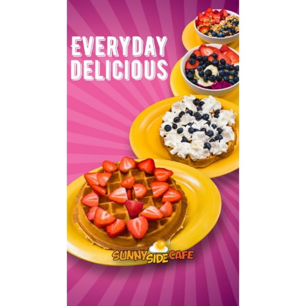 Waffles with strawberries, whipped cream, blueberries, and fruit bowls on yellow plates against a pink background.
