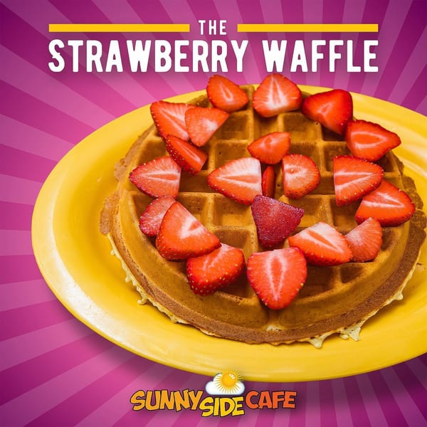A golden-brown waffle topped with numerous fresh, sliced strawberries on a yellow plate.