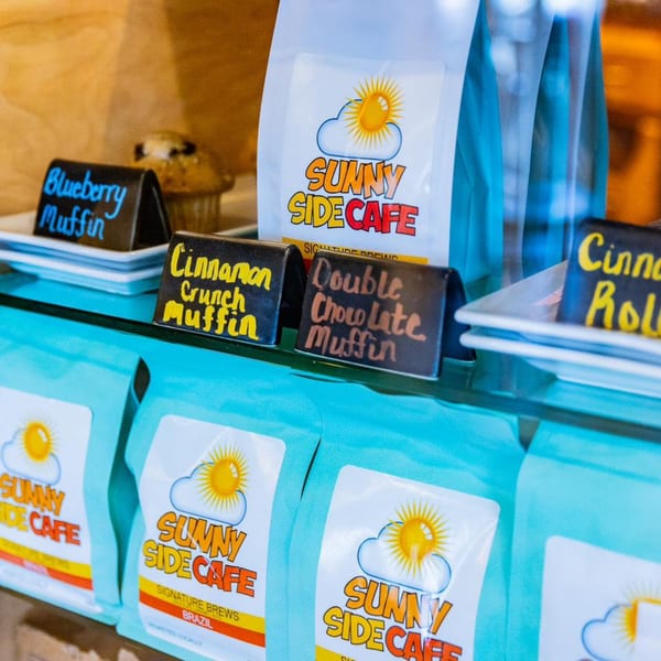 Sunny Side Cafe coffee bags and muffin signs for blueberry, cinnamon crunch, and double chocolate.