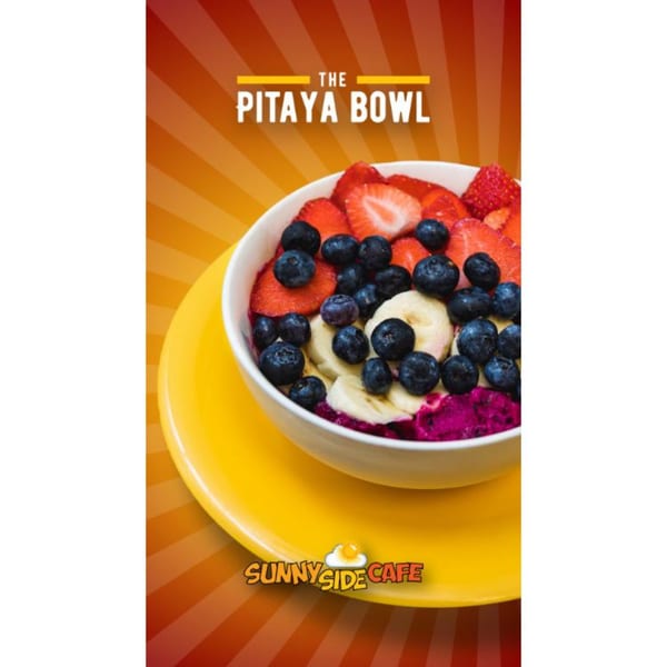 A vibrant pitaya bowl from Sunnyside Cafe, topped with fresh strawberries, blueberries, and banana slices.